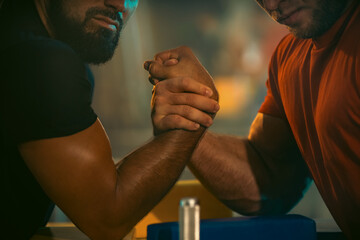 Fototapeta na wymiar The Armwrestling. Two strong athletes in the gym compete in arm wrestling. Bodybuilders armwreslers in athletic training room