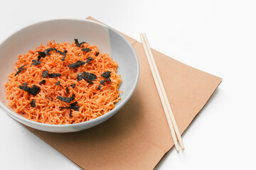 Korean instant noodles menu in a white bowl on brown paper with chopsticks on the side, close-up shot against a white background. Used in food and health applications