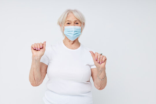 Photo of retired old lady in casual t-shirt and medical mask isolated background
