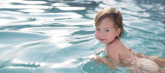 A little pretty girl swims with support in the pool