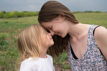 Sisters kissing. Happy family. Outdoor picture of senior sister giving a kiss to her sister