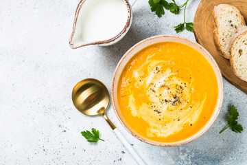 Pumpkin soup puree with cream in the bowl. Top view image at white table.