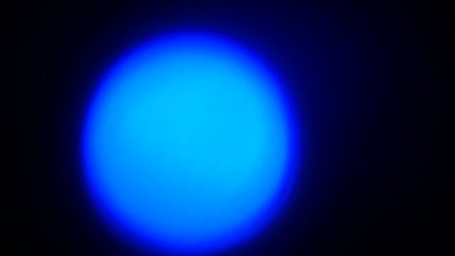 Glowing blue and white light sphere on blue, black background.