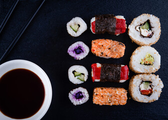 vegetarian sushi set  with chopsticks and soy on a black plate on black background 