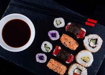 sushi set  with chopsticks and soy on a black plate ready to eat  on black background 