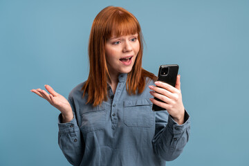 Woman gesturing with hand, looking at the screen while having online conversation on smartphone