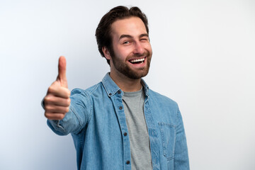 Caucasian man standing happy and positive with thumbs up approving with a big smile