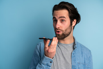 Recording voice message. Caucasian man's modern portrait on blue studio background