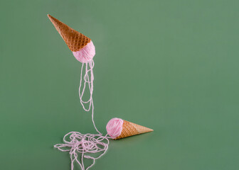 two waffle cones with pink yarn instead of ice cream hobby concept on pink background	