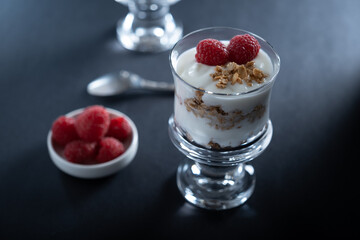 Two glass bowls of vanilla yogurt with cinnamon roll granola and raspberry topping
