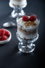 Two glass bowls of vanilla yogurt with cinnamon roll granola and raspberry topping