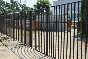 part of a black metal fence wall made of iron rods in the street