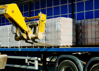 HGV delivered concrete blocks on construction site and telehandler offloading it © Iryna