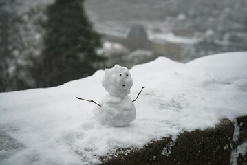 Сhristmas snowman standing on a concrete wall covered with snow