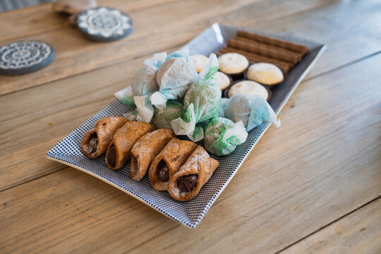 A selection of Italian dessert and sweet treats arranged on a blue and white plate. Food image of sweets and snacks on wooden table with copy space available. 