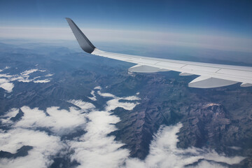 airplane wing above mountains and clouds