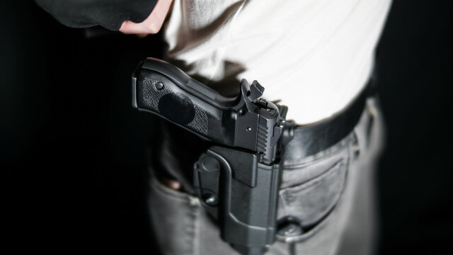 Man moving jacket to reveal a holstered firearm. Open carry and second amendment concept
