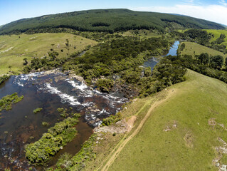 Fototapeta na wymiar Aerial view of Waterfall with fields, rocks and dirty road