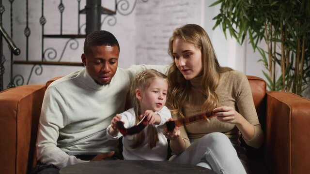 Man woman and little girl look at negatives in living room