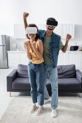 Excited african american couple showing yes gesture while gaming in vr headsets at home.