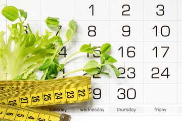 Micro greens peas, lettuce leaf and a measuring tape on the calendar grid. The concept of diet,...