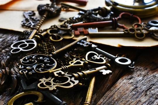A low angle image of several small vintage keys with a gold colored pocket watch. 