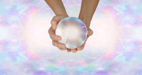 Fortune Teller's crystal ball header background - female holding large clear scrying ball against a wide pale ethereal symmetrical pattern background with copy space either side
