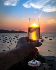Taça de espumante com o por do sol colorido ao fundo junto ao mar.