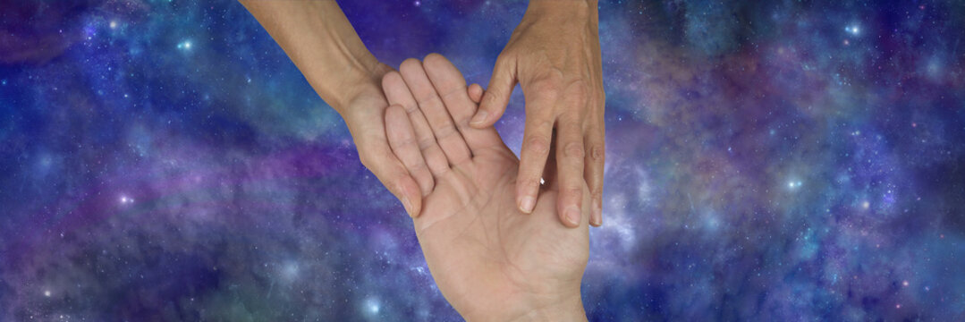 Female giving Palm reading to male - woman holding a man's open palm identifying lines against a wide celestial dark blue night sky background with copy space both sides 
