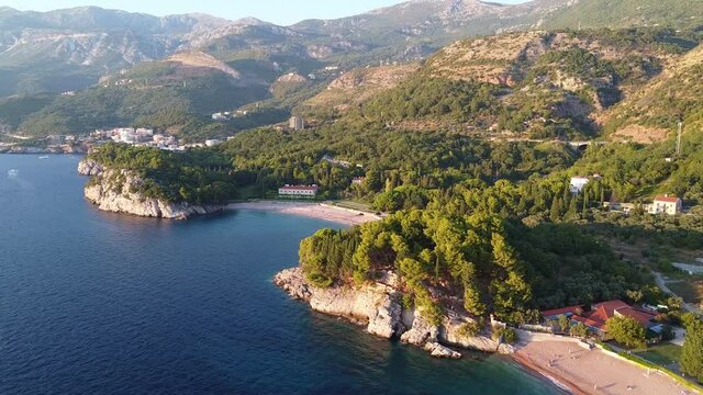 Drone view of quiet sea bay at the foot of big mountains. There is also a cozy beach. Drone Shot of King's Beach (Milocer Beach) in Montenegro.