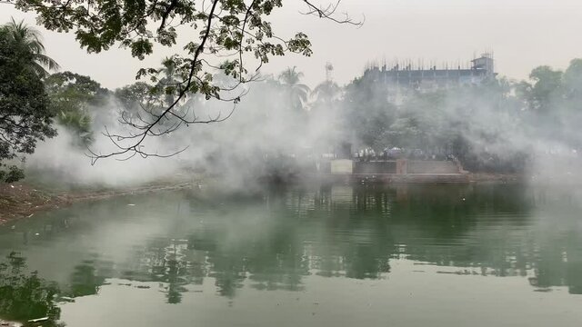 Fog From Insecticide Spray Floating Over Park Pond In Dhaka. Pan Right