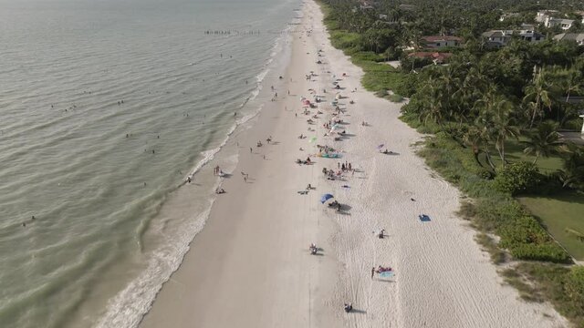 People enjoy white sandy ocean beach on sunny warm Florida gulf coast