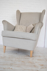 Close-up of stylish armchair with pillows. Minimalist cozy interior. Home decor