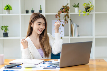 Young Asian businesswoman working with graphs and laptops analyzing marketing finance data in the office