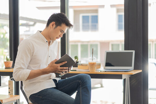 Young Asian man working on a laptop with tiger skin and a cup of coffee next to the concept of learning to work in a coffee shop.