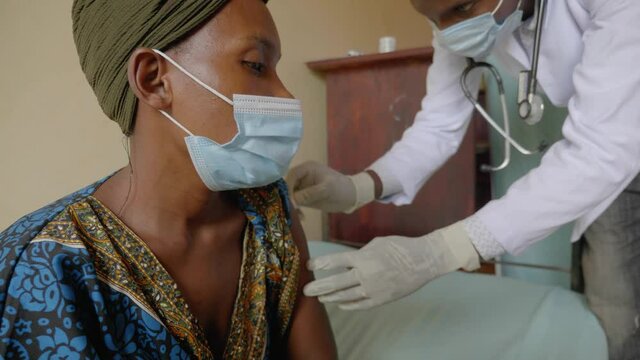 Close up shot of an African woman being vaccinated by an African doctor in a rural clinic.