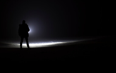 man with flashlight in winter night
