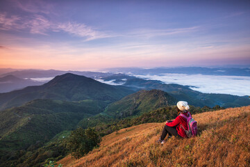 Obraz premium Young woman in red jacket hiking on high mountains and sea of mist . Doi Pui Ko, Mae Hong Son Province, Thailand.