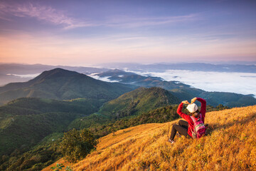 Fototapeta na wymiar Young woman in red jacket hiking on high mountains and sea of mist . Doi Pui Ko, Mae Hong Son Province, Thailand.