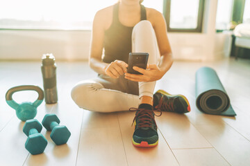 Fitness app on mobile phone for exercise at home. Woman using tech device during strength training...