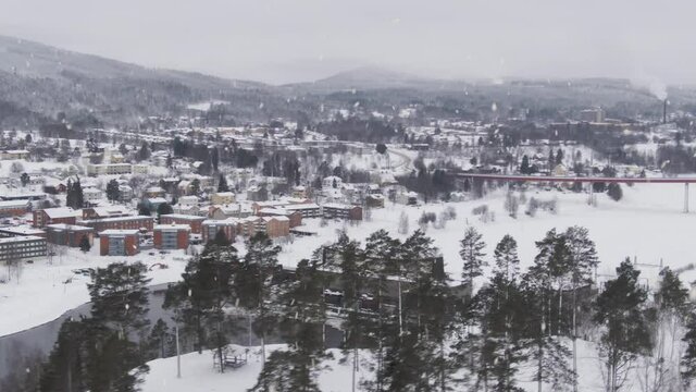 Small Swedish town in winter mountain landscape during snowfall, aerial shot