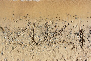 New Year 2022. Message written on the background of a sandy beach. hello concept for the upcoming new year 2022. New Year Christmas. with copy space for text. Close-up and top view of shiny