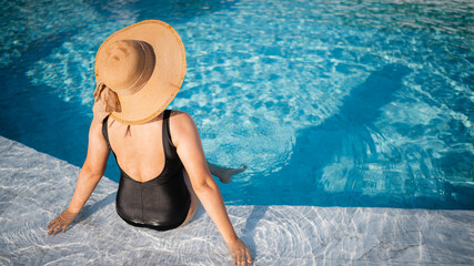 Young woman sitting in the pool in luxury resort, travel concept and banner cover background summer.