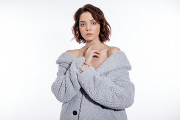 High fashion photo of a beautiful elegant young woman in a pretty pale blue fur coat, suede boots posing over white background. Make up, hairstyle. Slim figure.