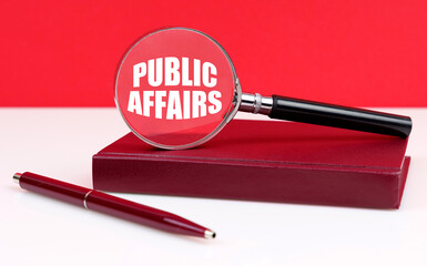 On a white and red background, a notebook, a pen and a magnifying glass, inside which the inscription - Public Affairs