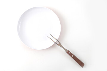 A white plate and stainless steel fork, usually used for eating steak