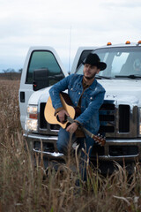 JOVEN MEXICANO CANTANDO CON SU GUITARRA USA SOMBRERO Y TIENE BARBA