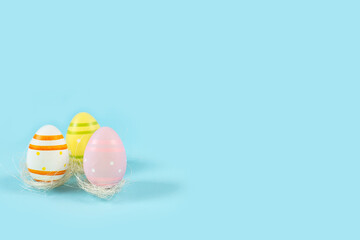Color Easter eggs in white nest on a blue background.