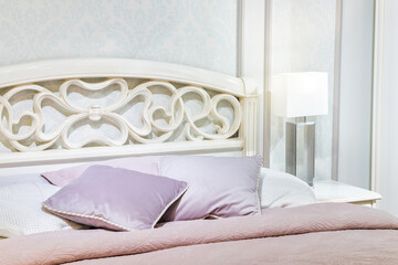 Bedroom interior, bed with pillows and blanket, lamp is on the bedside table