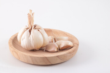 A few cloves of garlic placed on a small wooden plate.